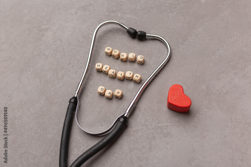 World health day concept. Stethoscope, red heart and text World Health Day on grey background. Global health care