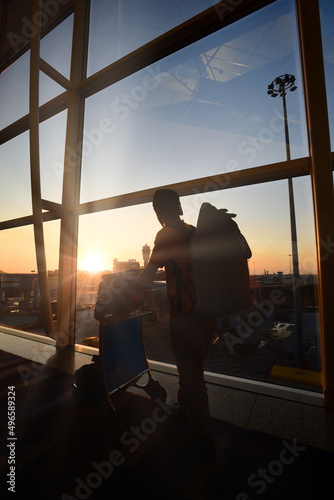 Silhouette of man with luggage standing near window in airpor