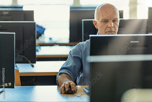middle-aged man uses a desktop PC workstation in a common room