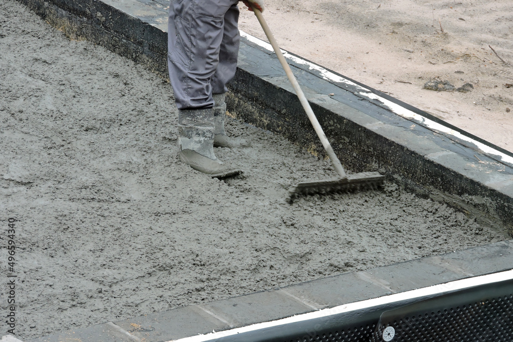 A builder levelling and spreading concrete with a rake A builder levelling and spreading concrete with a rake