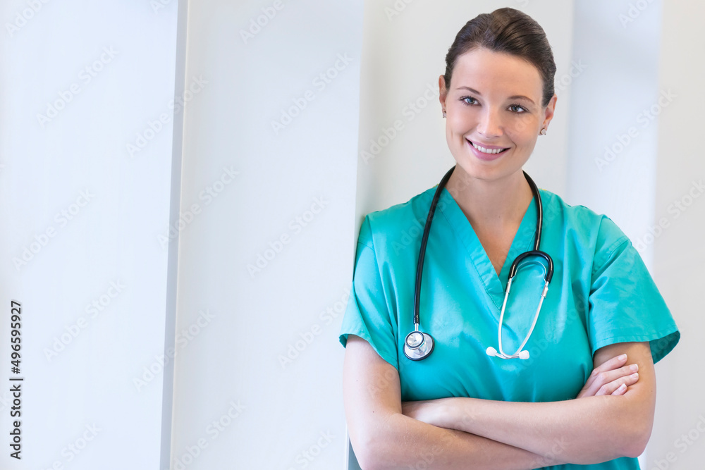Caucasian female clinical nurse wearing scrubs in hospital corridor Caucasian female clinical nurse wearing scrubs in hospital corridor