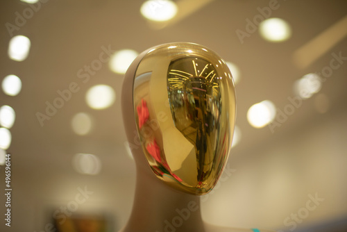 Golden mask on mannequin. Reflection in showcase.Figure of person.
