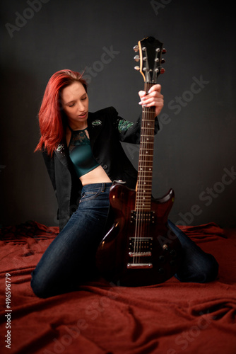 Photography Sexy and brutal rocker punk or metal red-hair girl with an electric guitar in a