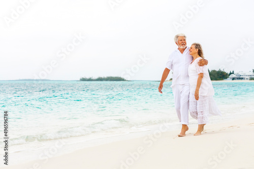 Attractive senior Caucasian couple in white living an island lifestyle on beach