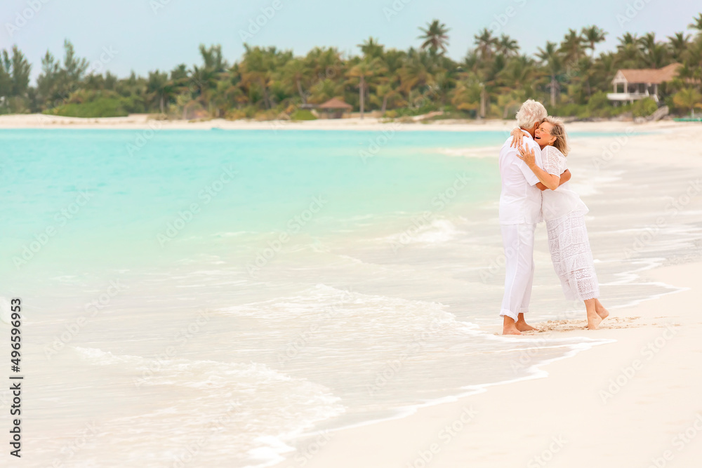 Happy mature Caucasian couple walking outdoors together on tropical beach Happy mature Caucasian couple walking outdoors together on tropical beach