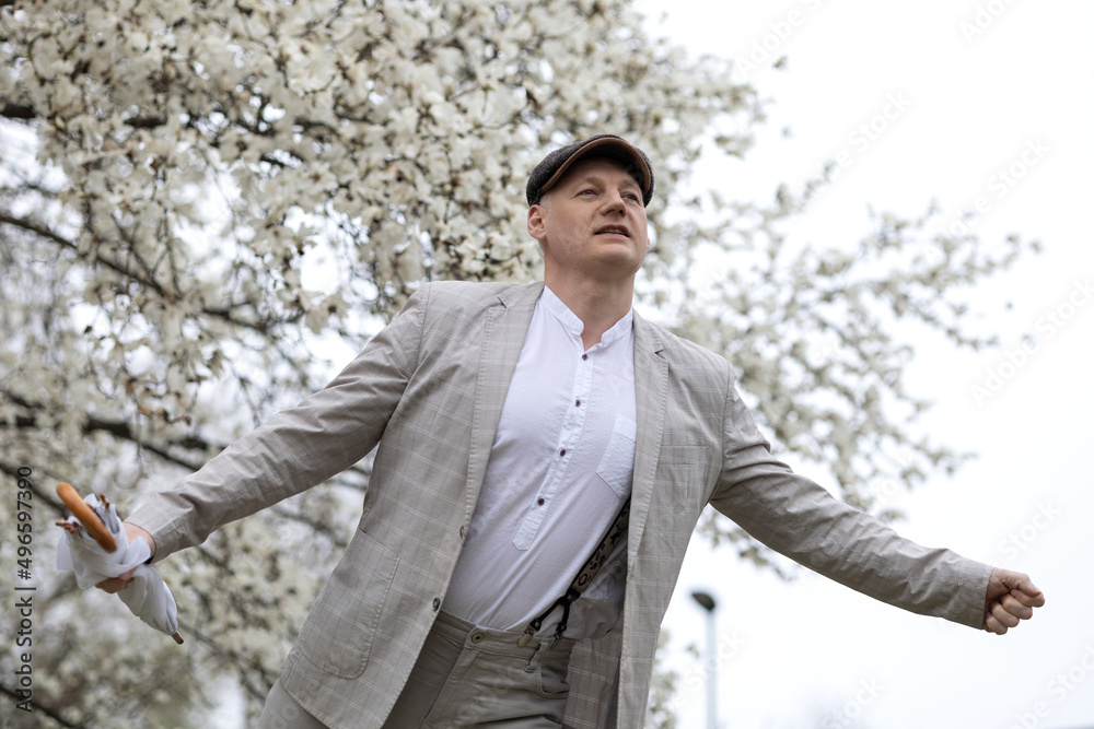 Beautiful smiling man on the background of white flowering magnolia Beautiful smiling man on the background of white flowering magnolia