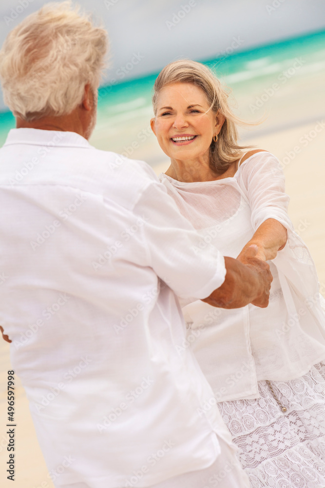 Fototapeta premium Happy mature Caucasian couple in white dancing beside ocean on tropical beach