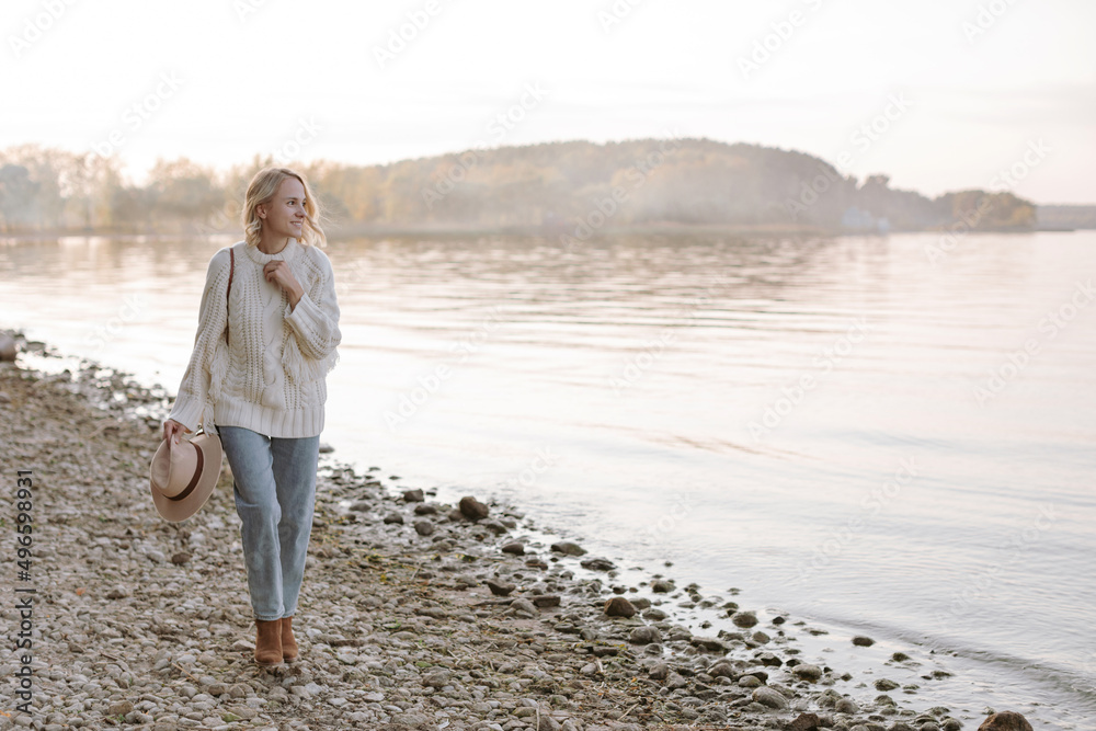 Woman happily jumps on the shore of the lake at sunset. Picturesque landscape.