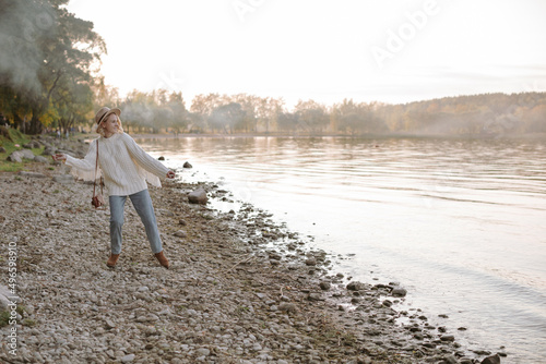 Foto A female tourist looking at the lake at sunset and throwing pebbles into the water