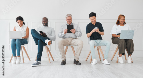 Making a few worthwhile connections while they wait. Shot of a diverse group of people using digital devices while sitting in line against a white background.