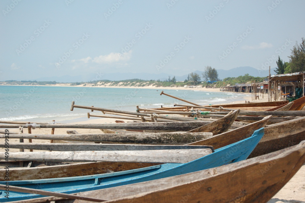 Small wooden fishing boats with paddles on a sandy beach in Vietnam.