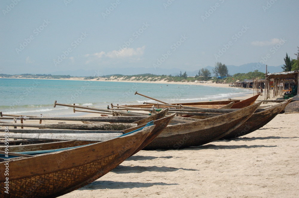 Small wooden fishing boats with paddles on a sandy beach in Vietnam.