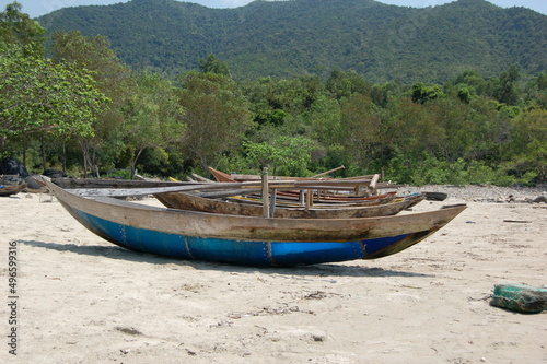 Small wooden fishing boats with paddles on a sandy beach in Vietnam.