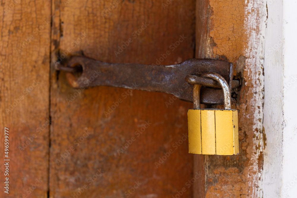 Padlock on an old brown wooden door with cracked paint. Close-up Padlock on an old brown wooden door with cracked paint. Close-up