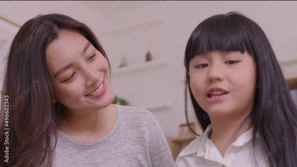 Asian mom talking to her baby girl with gentleness while he is resting on her laps on the sofa at home Asian mom talking to her baby girl with gentleness while he is resting on her laps on the sofa at home