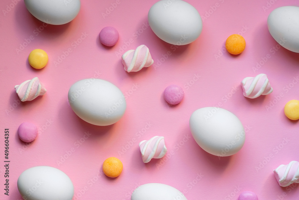 Pattern with eggs, candies, and marshmallows on pink background. Easter holiday concept. Pattern with eggs, candies, and marshmallows on pink background. Easter holiday concept.