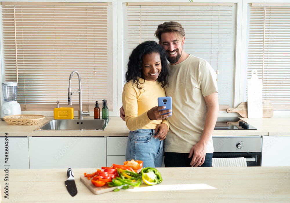 Smiling young multiethnic heterosexual couple looking at mobile phone Smiling young multiethnic heterosexual couple looking at mobile phone