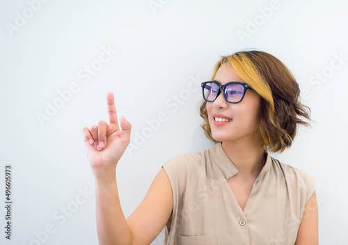 Happy smile Asian woman short hair wearing eyeglasses with blue filter touch on virtual touch screen by finger on white background. Hand point or press on empty space by businesswoman s hand.