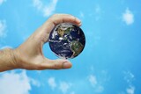 human hand holding the world earth above blue natural background. Safe world concept. Elements of this image furnished by NASA