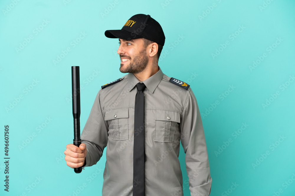 Young security man isolated on blue background looking side