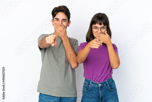 Young couple isolated on isolated white background pointing with finger at someone and laughing