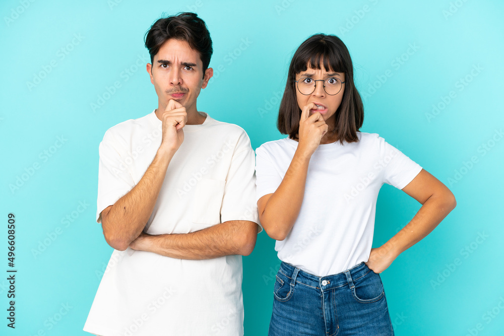 Young mixed race couple isolated on blue background having doubts while looking up Young mixed race couple isolated on blue background having doubts while looking up