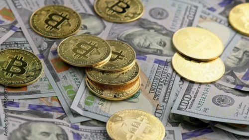 rotating bitcoin coins scattered over US dollar banknotes, closeup photo