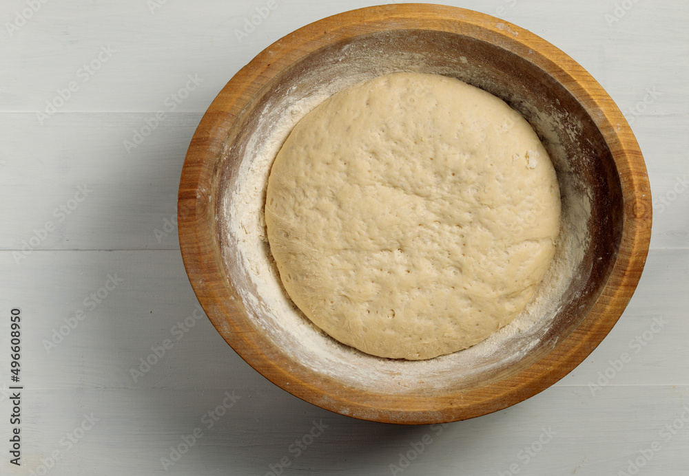 Wooden bowl with yeast dough. Close-up, top view. Wooden bowl with yeast dough. Close-up, top view.