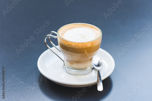 Creamy coffee in a glass cup on a dark table.