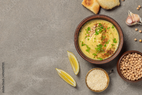 Chickpea or pea paste in a brown bowl. On a gray background, with pita bread and cooking ingredients. photo