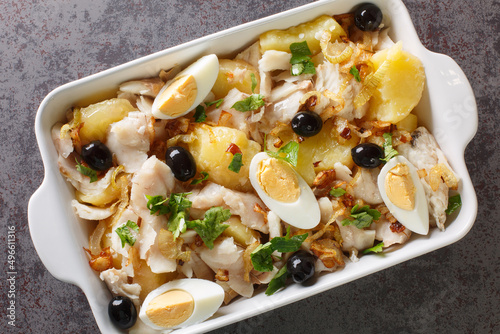 Obraz na płótnie Portuguese Bacalhau a Gomes de Sa salted cod baked with potatoes, onions served with eggs and olives close-up in a baking dish on the table. horizontal top view from above w salonie