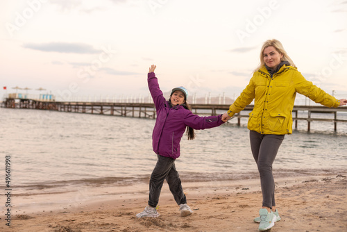 mother and daughter on the beach. It's cold on the beach. Girl on the beach in Egypt in winter. A child at sunset