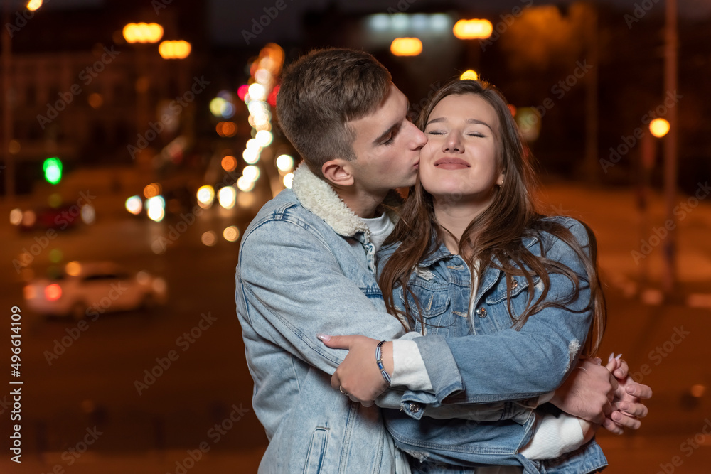 Guy gently hugs and kisses his girlfriend on evening city background Guy gently hugs and kisses his girlfriend on evening city background