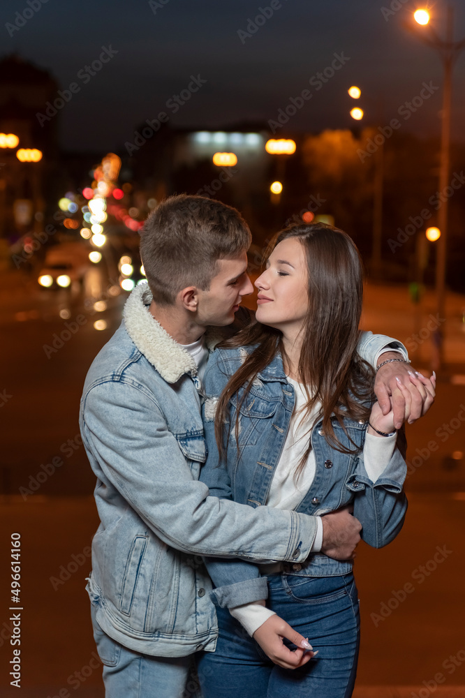 Young beautiful couple hugging on evening city background. Vertical frame