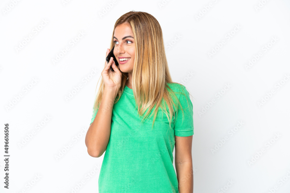 Blonde Uruguayan girl isolated on white background keeping a conversation with the mobile phone with someone Blonde Uruguayan girl isolated on white background keeping a conversation with the mobile phone with someone