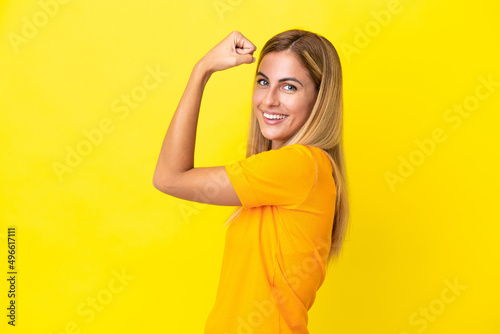 Blonde Uruguayan girl isolated on yellow background doing strong gesture
