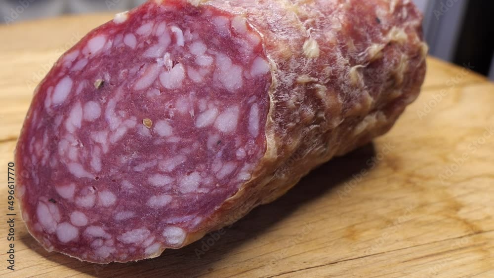 A piece of smoked sausage on a wooden cutting board. Close-up video. Half a sausage. A piece of smoked sausage on a wooden cutting board. Close-up video. Half a sausage.