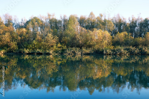 Autumn landscape with forest is reflected in the river water