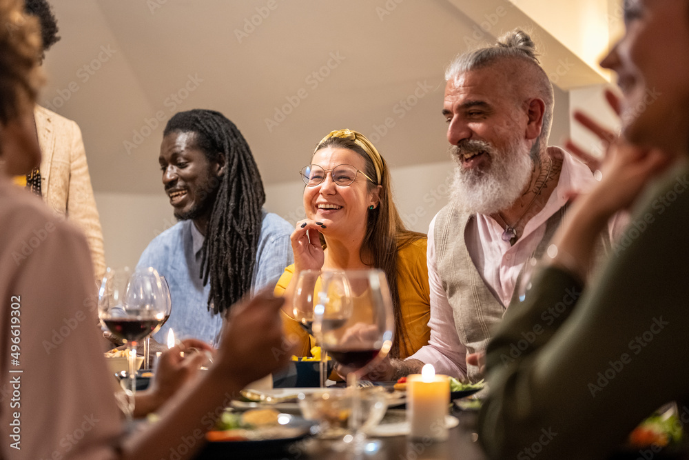 Group of diverse people sharing time and having fun at vegetarian dinner, mixed range age friends celebrating party at home, focus on curvy woman face