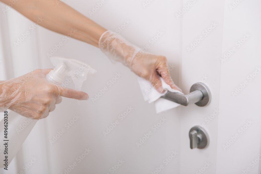 Cleaning door handles with wet wipe and white gloves. Sanitize surfaces prevention in hospital and public spaces against corona virus. Woman hand using towel for cleaning home room door link. Cleaning door handles with wet wipe and white gloves. Sanitize surfaces prevention in hospital and public spaces against corona virus. Woman hand using towel for cleaning home room door link.