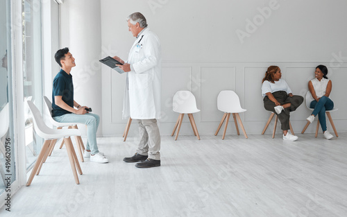 A visit to the doctor doesnt have to be a dreadful thing. Shot of a mature doctor meeting with a young man in the waiting room of a clinic.