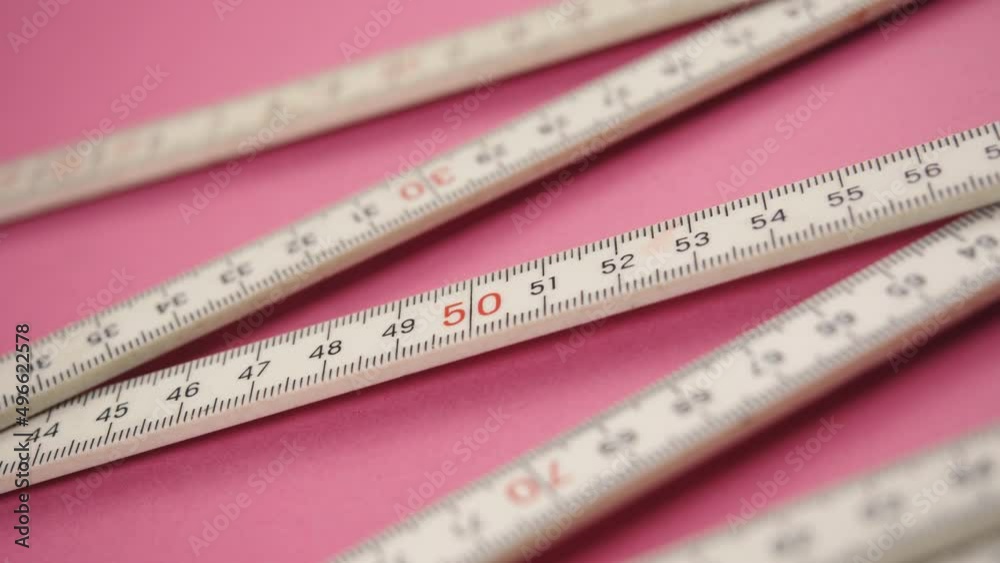 Folding Metric Carpenter Ruler on pink background. Tape measure tool. Flexible, collapsible. Measure size or distance or length. Plastic strip with linear measurement markings. Calculation centimeter. Folding Metric Carpenter Ruler on pink background. Tape measure tool. Flexible, collapsible. Measure size or distance or length. Plastic strip with linear measurement markings. Calculation centimeter.