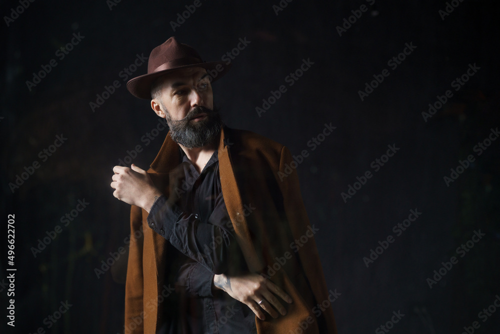 Portrait of mature bearded man in coat and hat. Mystical thriller concept. High quality photo