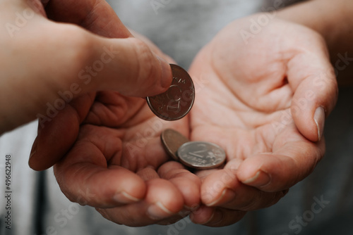 Poverty, financial social problems, poor, charity, help concept. Hand giving money in palms, close-up. Selective focus on coin