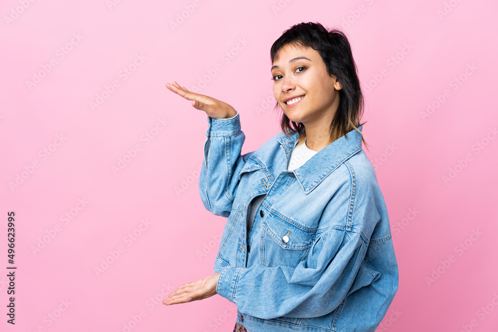 Young Uruguayan woman over isolated pink background holding copyspace to insert an ad