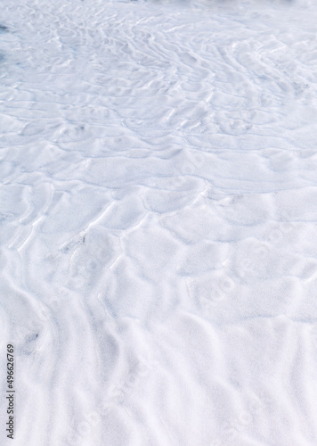 White structure of the snowy surface of ice floe of Baikal lake in early spring. Top view of snow with lines of wind in March. Cold winter abstract background. Flat lay, close-up, copy space, mock up