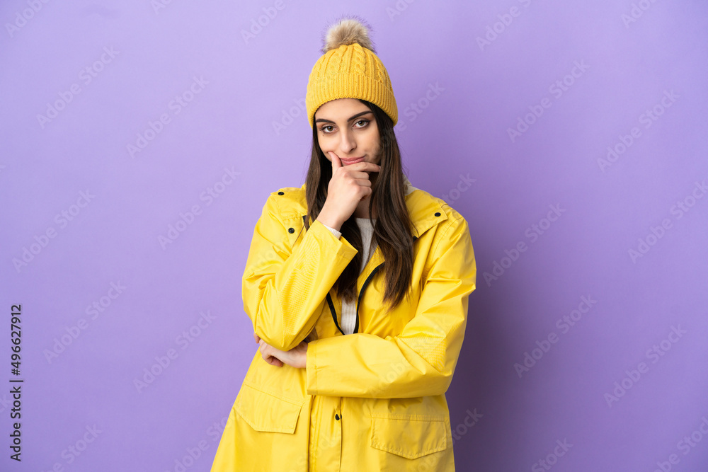 Young caucasian woman wearing a rainproof coat isolated on purple background thinking Young caucasian woman wearing a rainproof coat isolated on purple background thinking