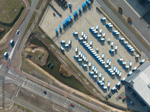 Top down supply chain distribution logistics depot. Aerial drone view of a commercial warehouse delivery trucks distribting merchandise. Amsterdam, The Netherlands.