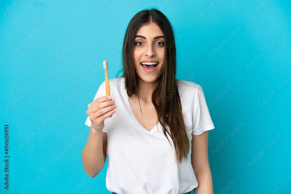 Young caucasian woman brushing teeth isolated on blue background with surprise and shocked facial expression Young caucasian woman brushing teeth isolated on blue background with surprise and shocked facial expression