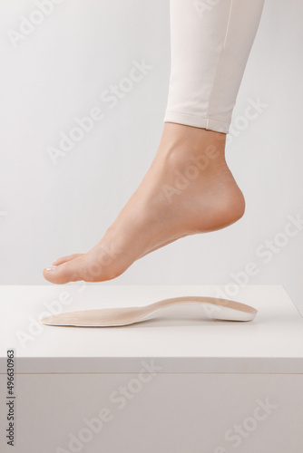 Medical insoles. Isolated orthopedic insoles on a white background. Treatment and prevention of flat feet and foot diseases. Foot care. Insole cutaway layers. Leg hanging over the insole.